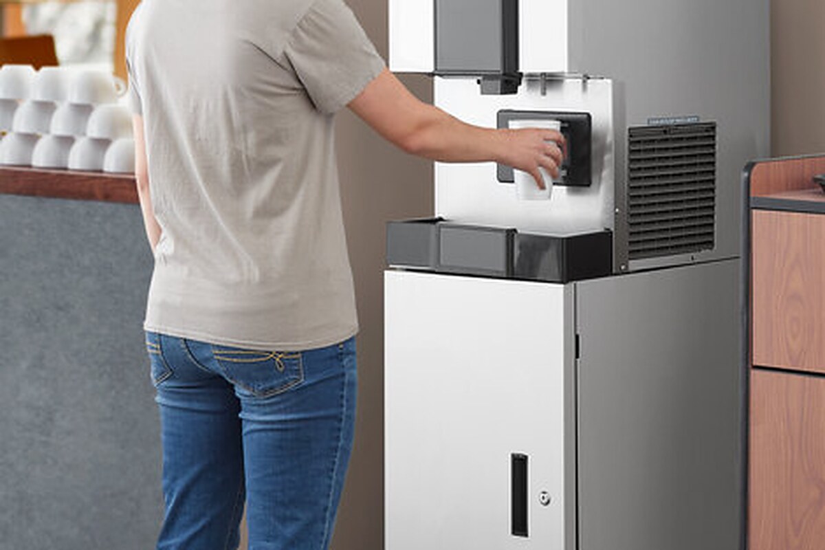 Employee filling a cup at a Hoshizaki countertop ice and water dispenser in an office break room
