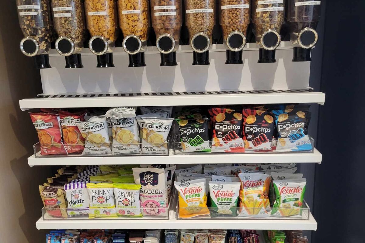 Office pantry with gravity-fed cereal dispensers above shelves of chips and snacks